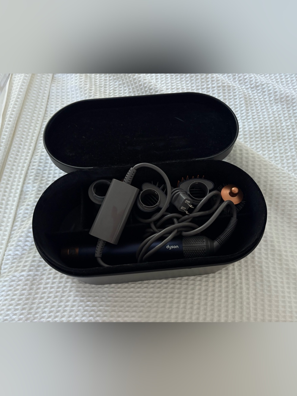 Dyson hair dryer with black and copper accents and magnetic attachments